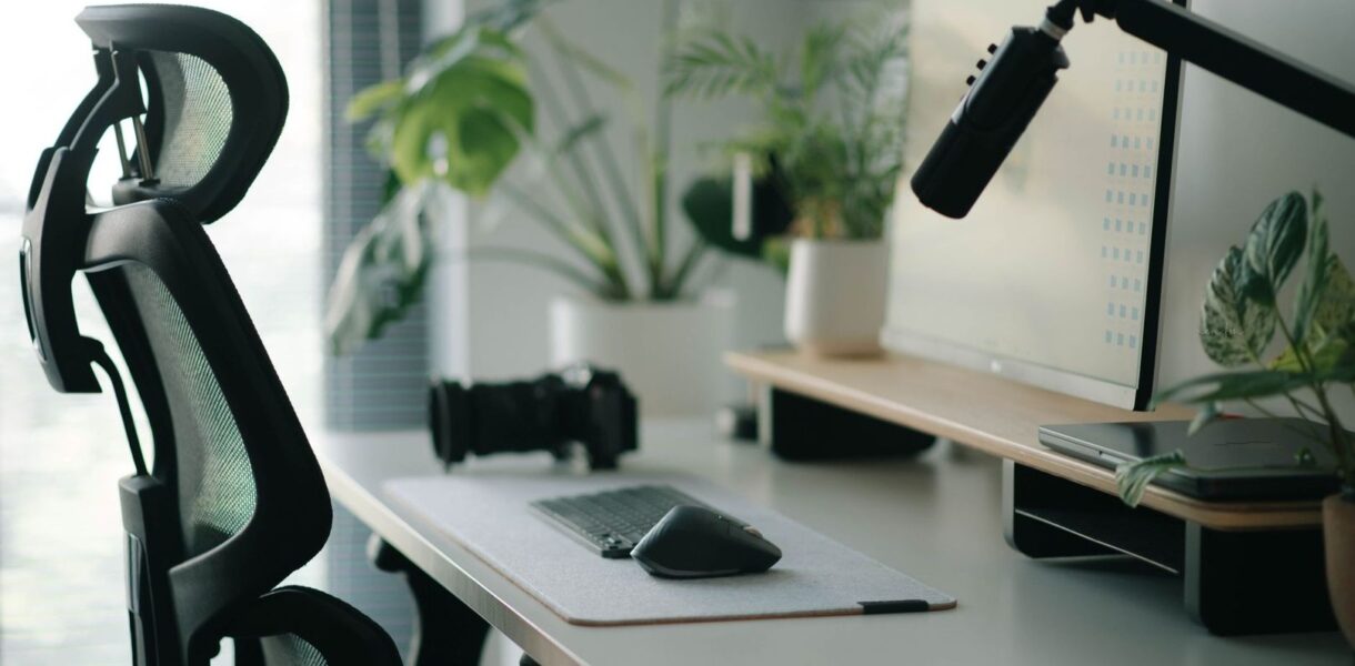Ergonomisk datorarbetsplats med kontorsstol, skärm, mus och mikrofon